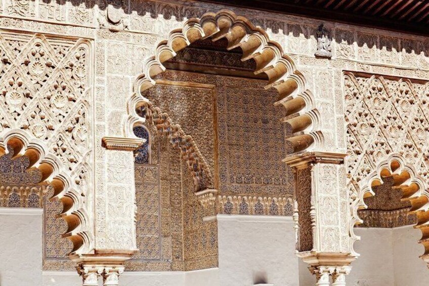 Un'elaborata porta d'ingresso con complesse decorazioni geometriche e floreali, incorniciata da colonne con archi a sesto acuto. 2