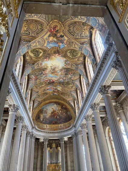 An ornate interior with a large fresco ceiling, classical columns, and intricate gold detailing. 5