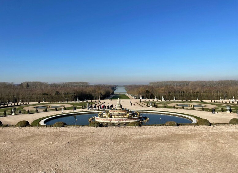 A formal garden with a central fountain, pathways, and statues. 2