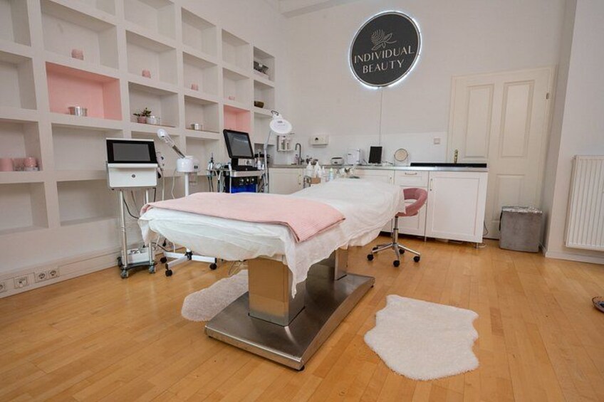 Et klinisk miljø med en behandlingsbriks, medicinsk udstyr og et skilt med teksten 'INDIVIDUAL BEAUTY'. 5