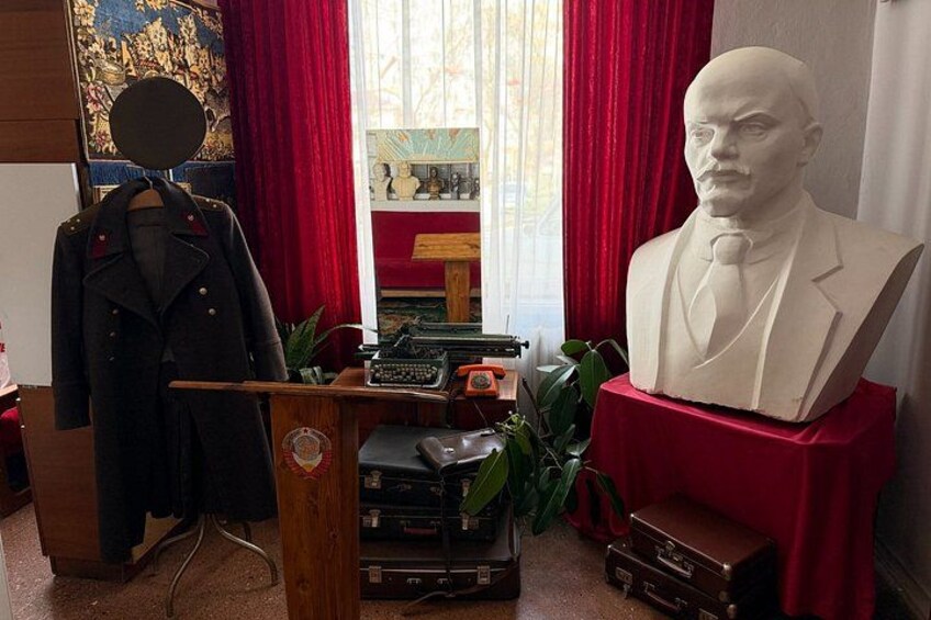 A room with a bust, a coat on a stand, and vintage items. 1
