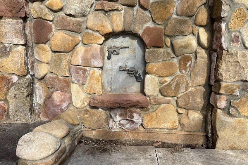 A stone wall with a small, rustic door featuring a metal latch. 5