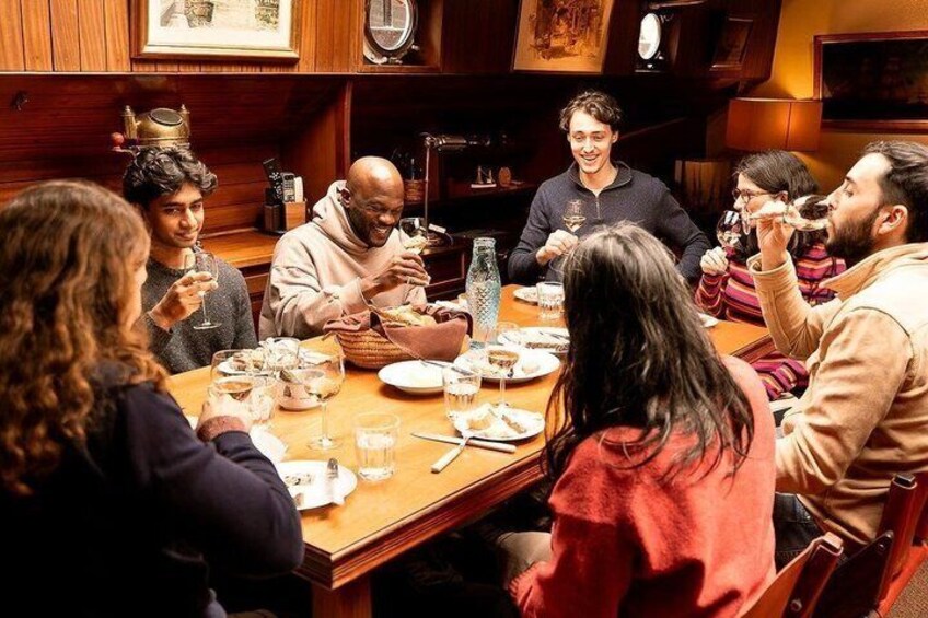 Un groupe de personnes est assis à une table en bois dans un restaurant et y prend son repas. 1