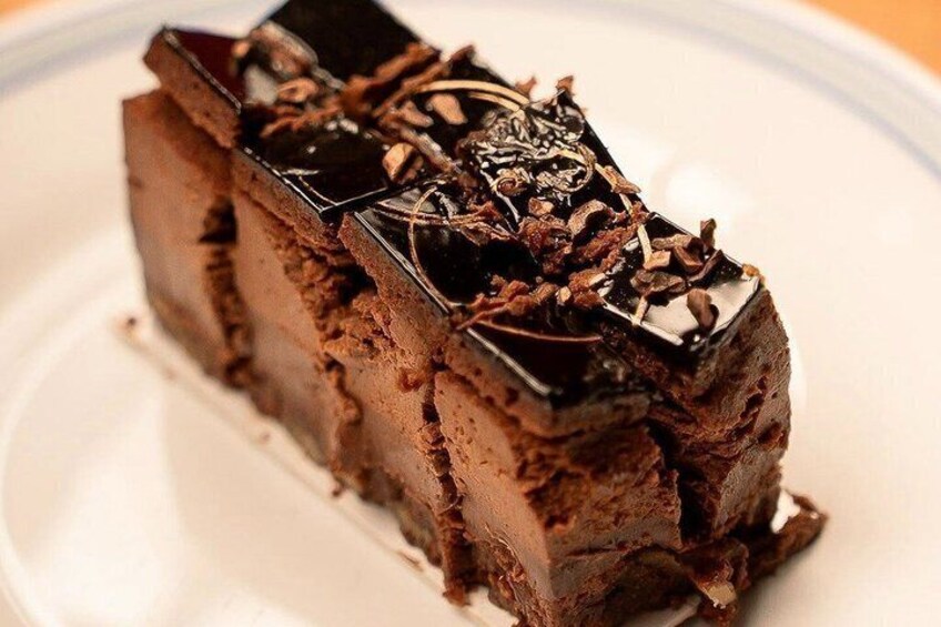 Une part de gâteau au chocolat, recouverte d’un glaçage brillant et de copeaux de chocolat. 3
