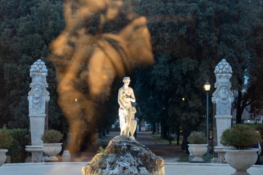 En staty i en park med träd och lyktstolpar. 3