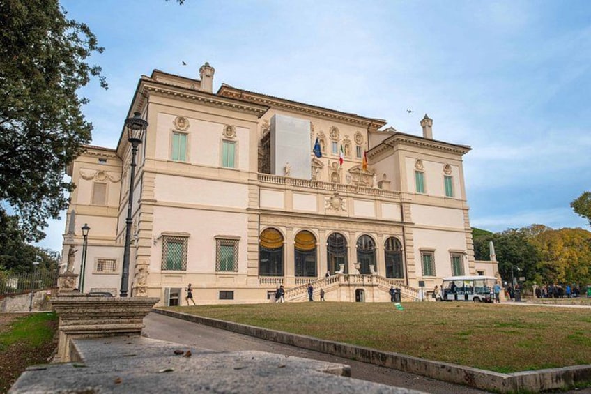 A large, classical building with a central staircase, arched windows, and a flag. 4