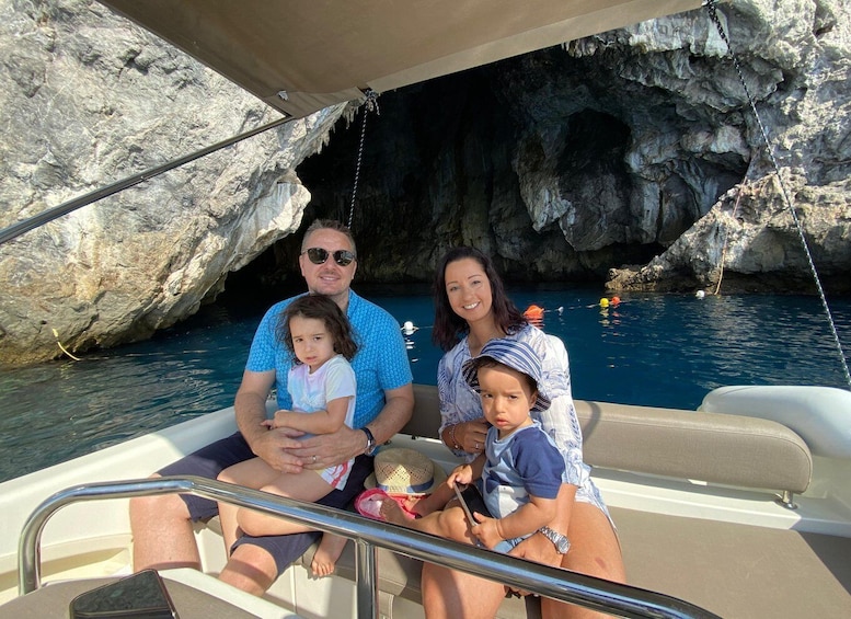 A family on a boat near a rocky cave entrance. 4