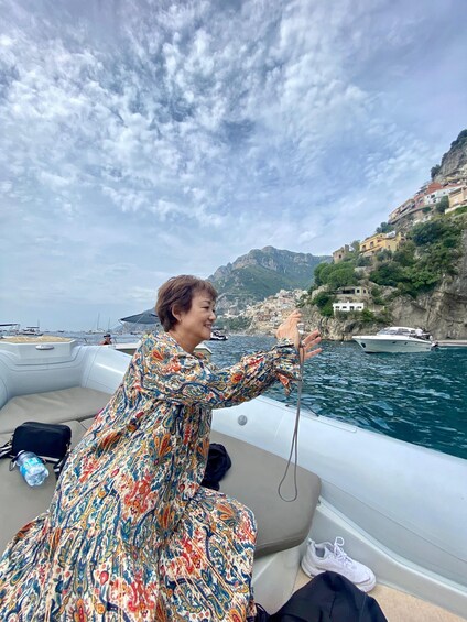 A person on a boat with a mountainous coastline in the background. 3