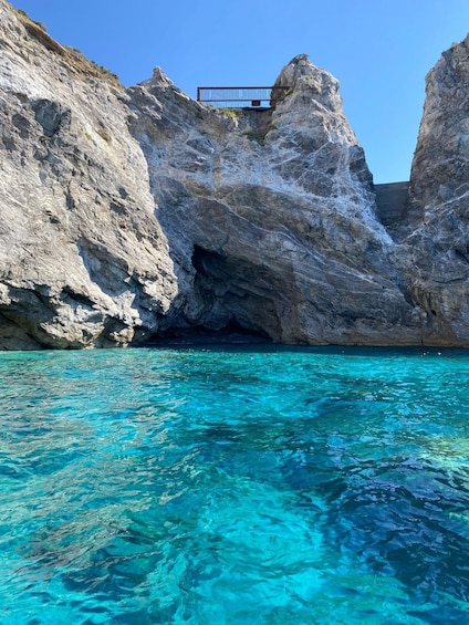 A rocky coastline with clear turquoise water and a small wooden structure on top of a rock formation. 2