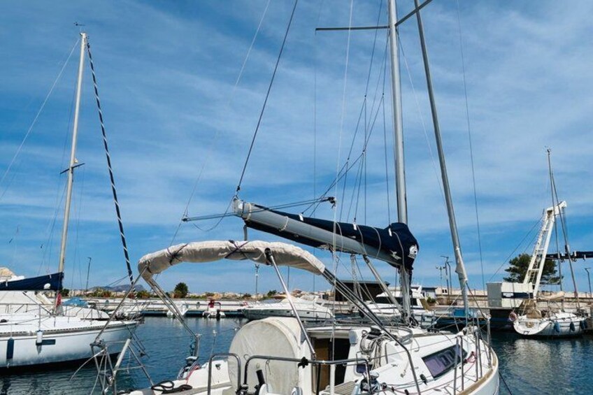 A marina with multiple sailboats docked, some with masts and sails, and a clear blue sky. 5