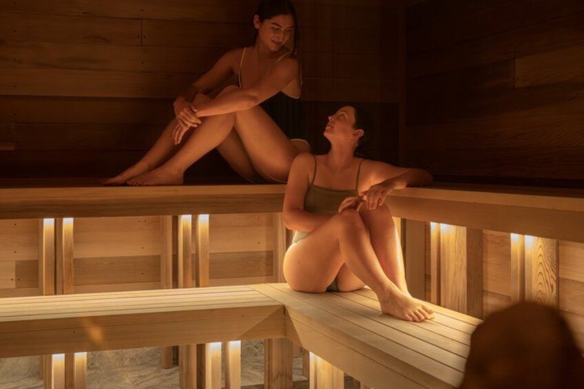 Zwei Personen sitzen auf Holzbänken in einer Sauna. 2