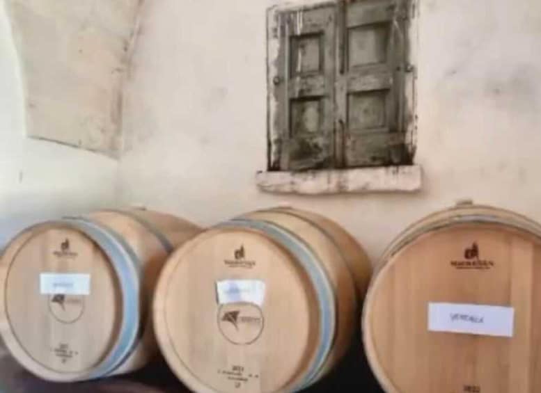 Three wooden barrels with labels, a rustic wall, and a small window. 4