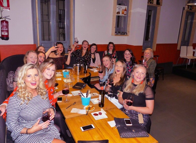 A group of people sitting around a table with wine glasses, plates of food, and a fire extinguisher on the wall. 3