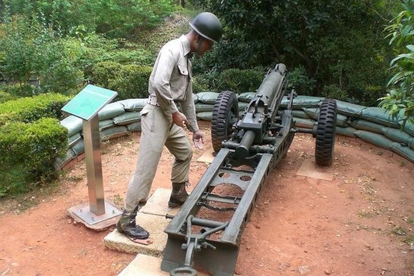 A man in military uniform operating a cannon in a garden. 4