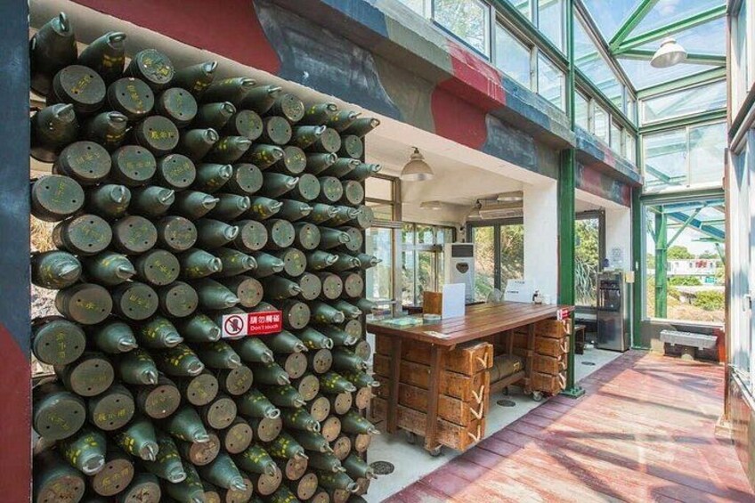 A greenhouse with a wall of ammunition, a wooden table, and a bench. 2