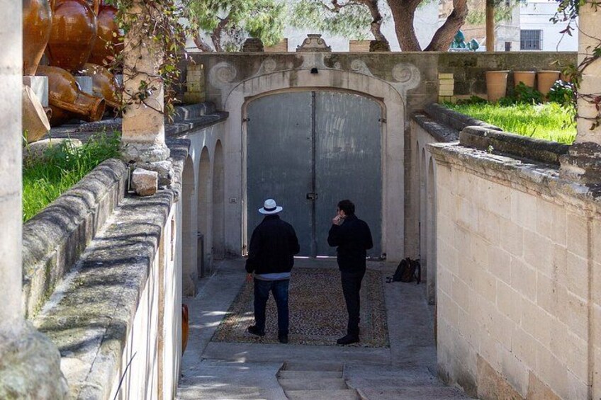 A stone pathway leading to a large, arched gate with two people standing in front. 4
