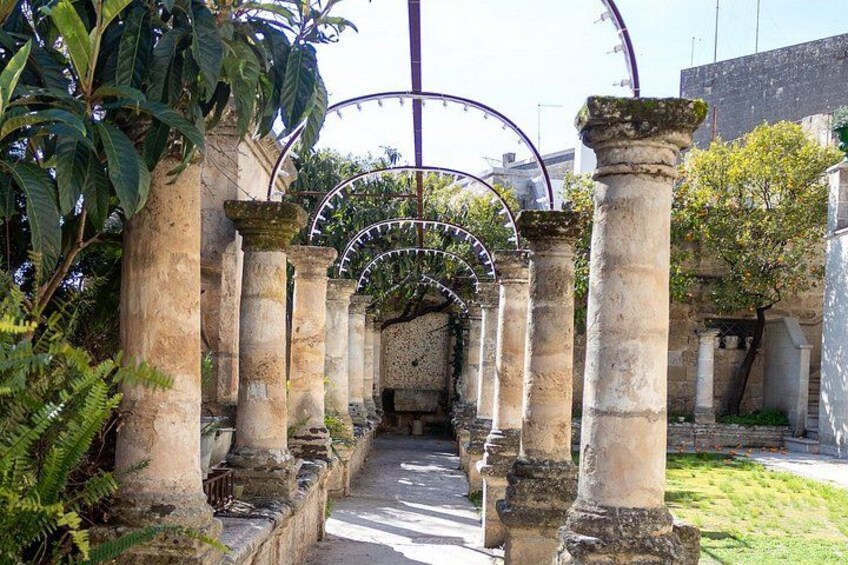 An ancient stone archway with columns, surrounded by greenery and a clear sky. 5