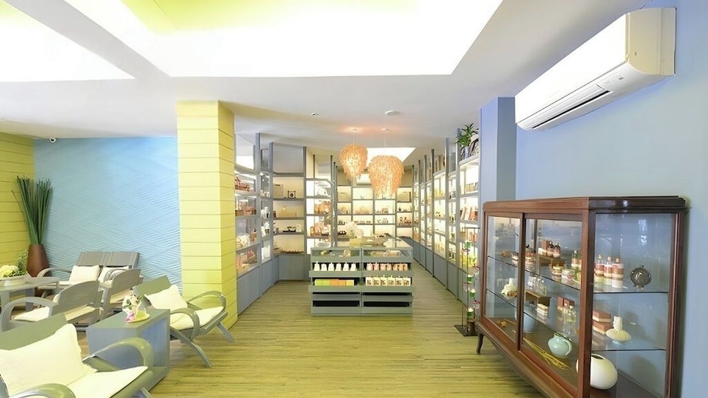 Un intérieur moderne avec un présentoir central où sont exposés les produits, des étagères remplies d’articles et des espaces aménagés pour s’asseoir. 2