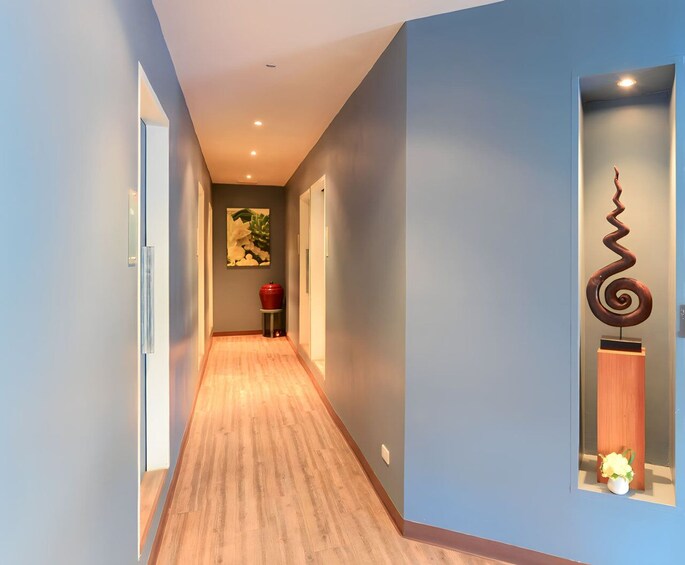 Un couloir aux murs bleu clair, doté d’un plancher en bois, d’une poubelle rouge et agrémenté d’une sculpture en spirale décorative. 5