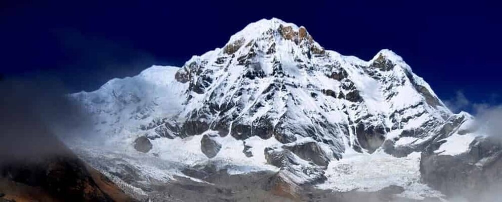 A snow-covered mountain peak with rugged terrain and a clear blue sky. 5