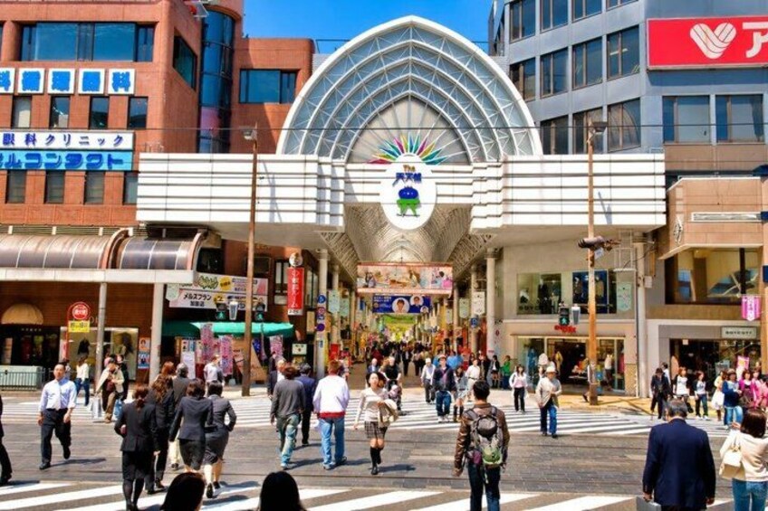 A busy urban street with a large, modern building featuring a distinctive glass dome and a colorful emblem. 5