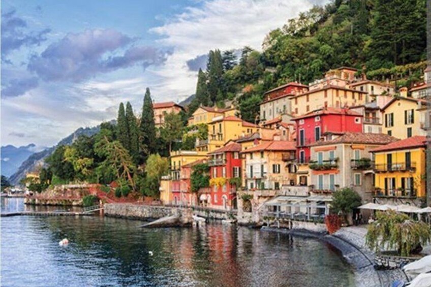 A coastal town with colorful buildings, a calm river, and a mountainous backdrop. 2