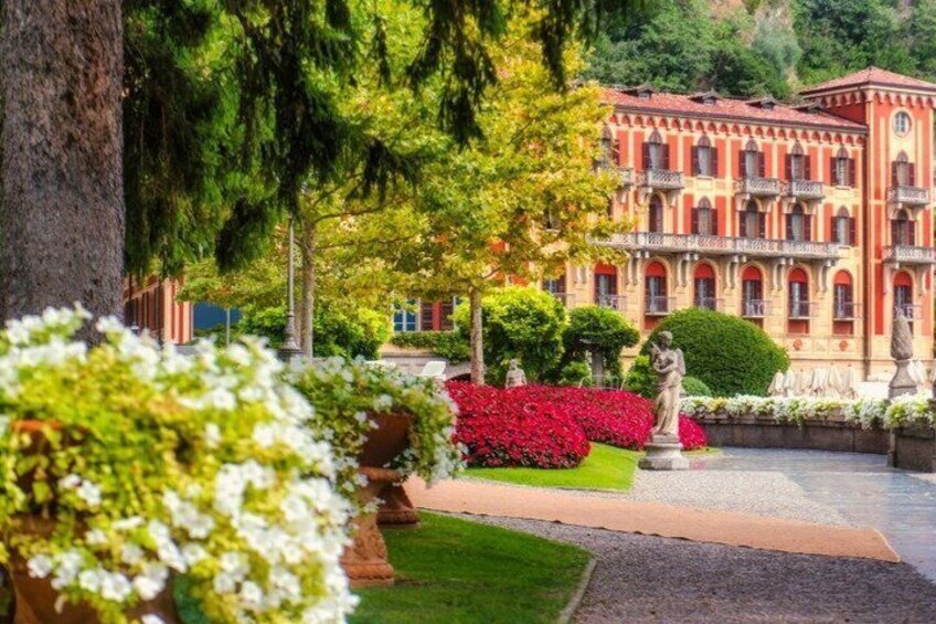 A landscaped garden with a statue, red flowers, and a building with balconies. 3
