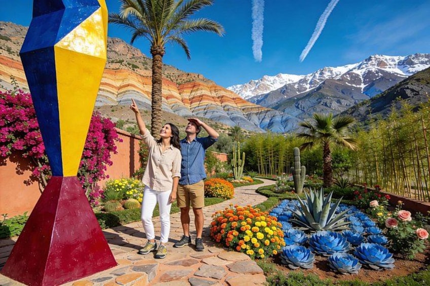 A couple in a garden with colorful flowers, a tall sculpture, and a mountainous backdrop. 1