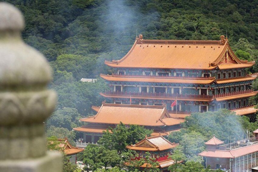Un templo tradicional de varios niveles con techo rojo, rodeado de abundante vegetación. 4