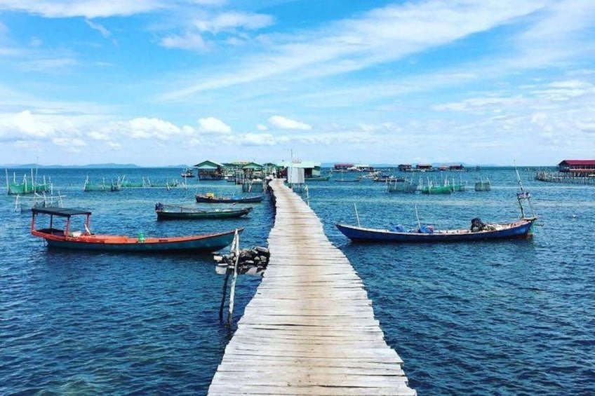 Un muelle de madera se extiende sobre aguas tranquilas, con varios barcos amarrados al final. 3