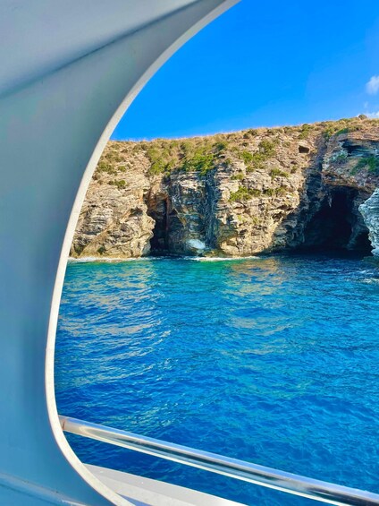 A boat's window view of a rocky coastline with clear blue water. 5
