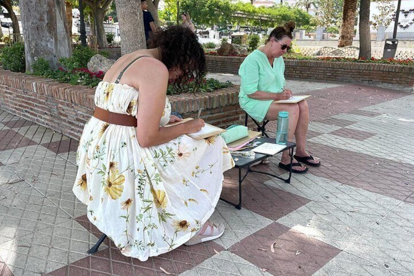 A woman in a floral dress sitting on a bench, reading a book. 3