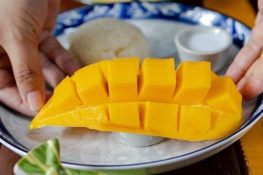 Un tazón de mango en rodajas, acompañado de una cuña de lima y un recipiente pequeño con salsa. 2
