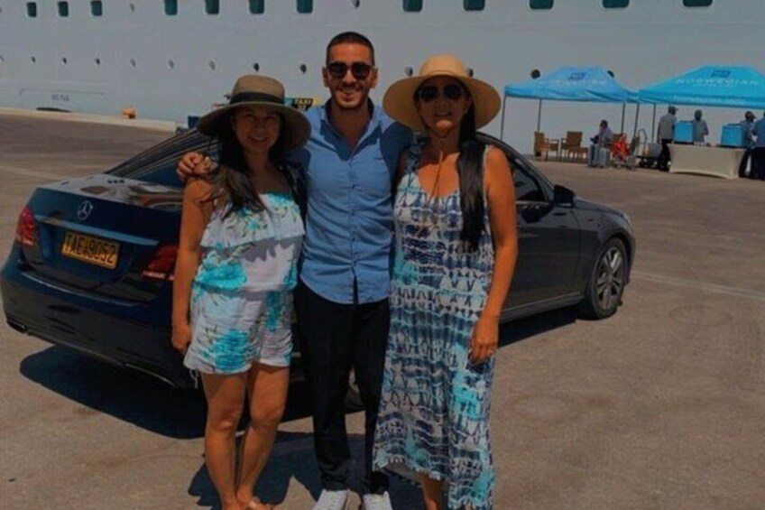 Three people standing in front of a car with a blue canopy in the background. 3