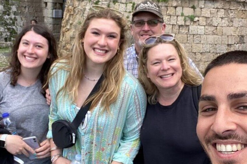 A group of people standing in front of a stone wall. 5