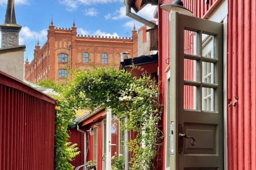 A red building with a white door, a red fence, and a red brick building in the background. 4