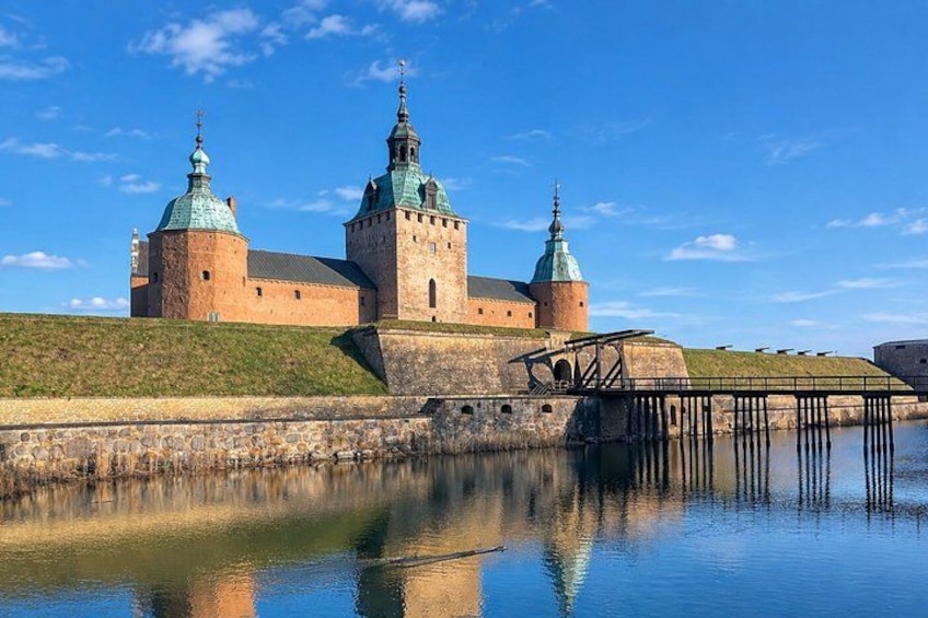 A historic castle with two prominent towers, a moat, and a wooden bridge. 5
