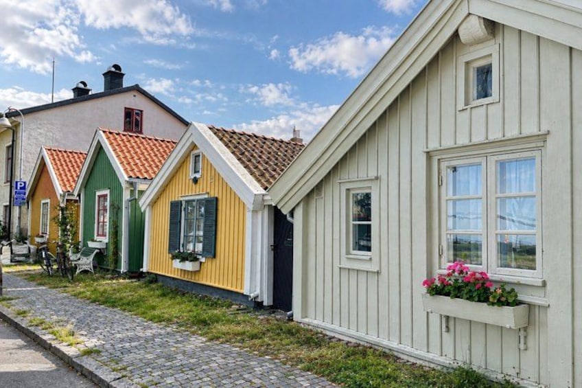 Colorful wooden houses with red-tiled roofs, a cobblestone path, and a clear blue sky. 2
