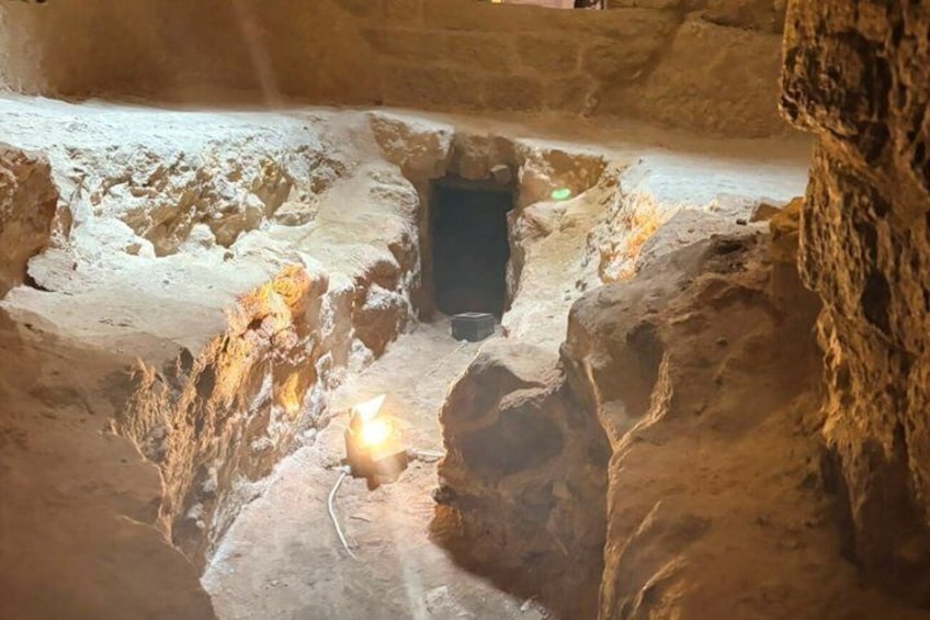 A cave with a central passageway, walls with rough textures, and a small light source at the bottom. 4