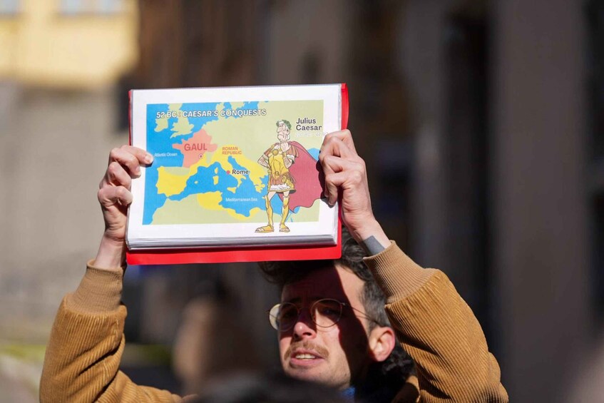 A person holding a book titled '52 BC: Caesar's Conquests' with a map and an illustration of Julius Caesar. 3
