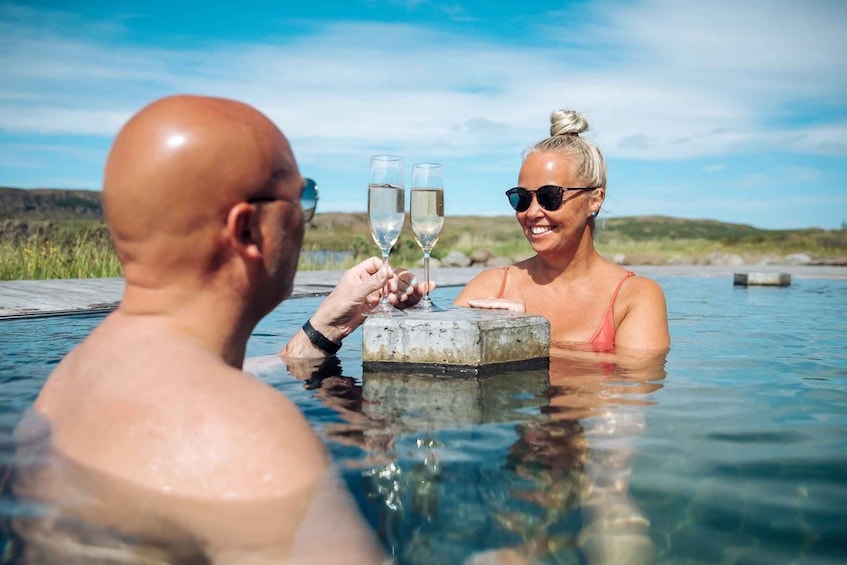 Two people in a hot spring with glasses of water. 3
