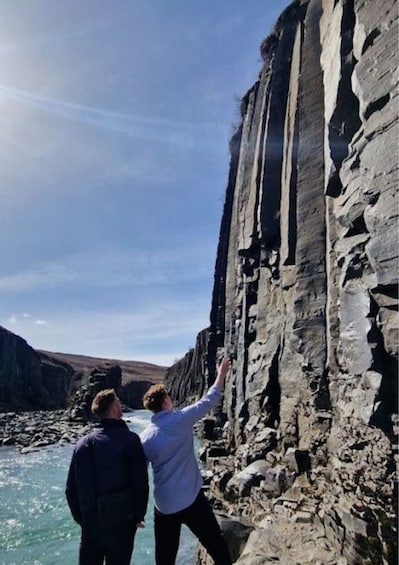 Two people standing on a rocky cliff by a river. 2