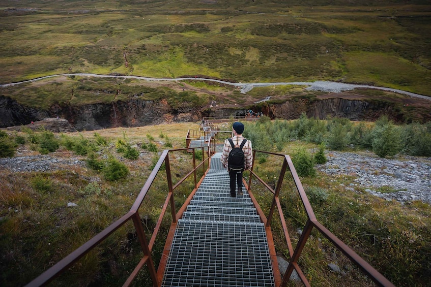A person walking up a metal staircase towards a scenic overlook. 4