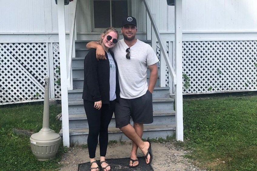 Two people standing on a porch with a white fence and steps. 2