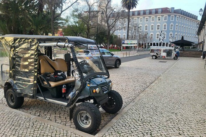 Un carrito de golf estacionado en una calle empedrada con un edificio al fondo. 2