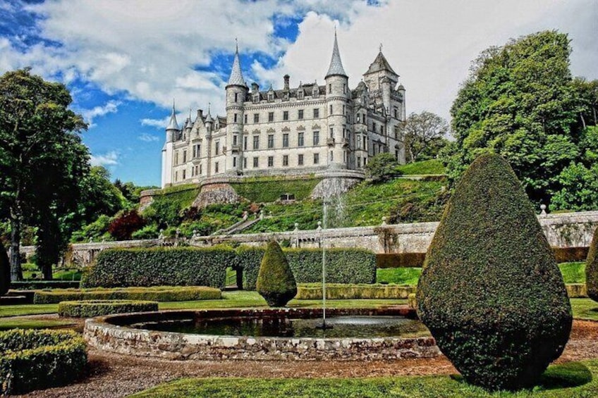A castle with a moat and topiary garden. 1
