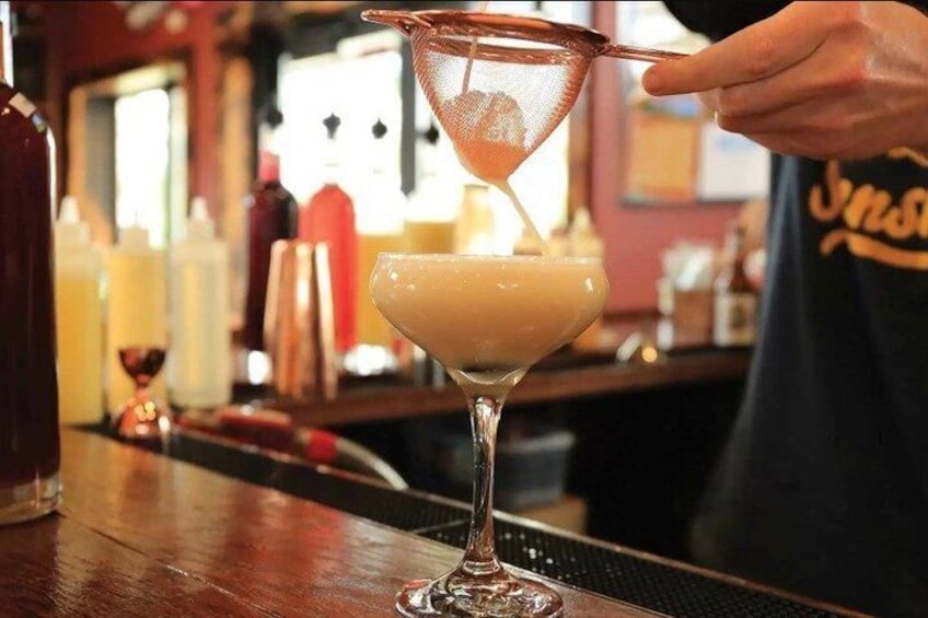 A bartender pouring a drink into a martini glass. 5