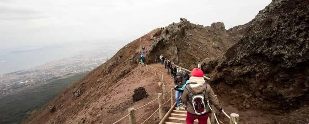 A mountain trail with wooden steps and a rope railing, surrounded by rocky terrain. 4