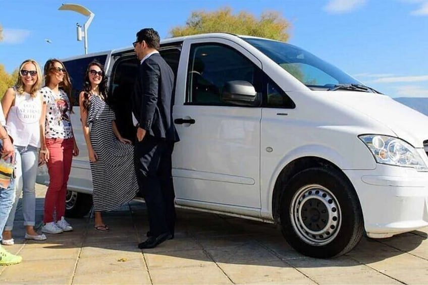 A white van parked on a paved surface with people standing nearby. 5