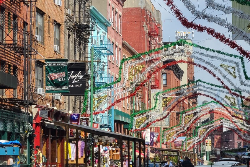 Een straat met gebouwen, waarvan sommige borden hebben voor pizza en espresso, en feestelijke guirlandes. 4